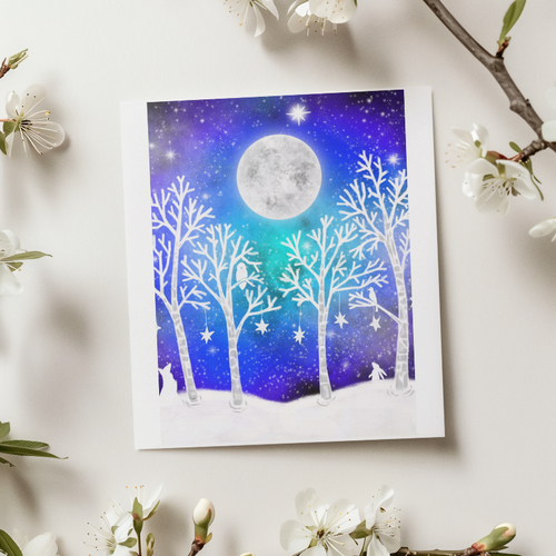 Card with a moon and tree design on a white surface with floral branches.