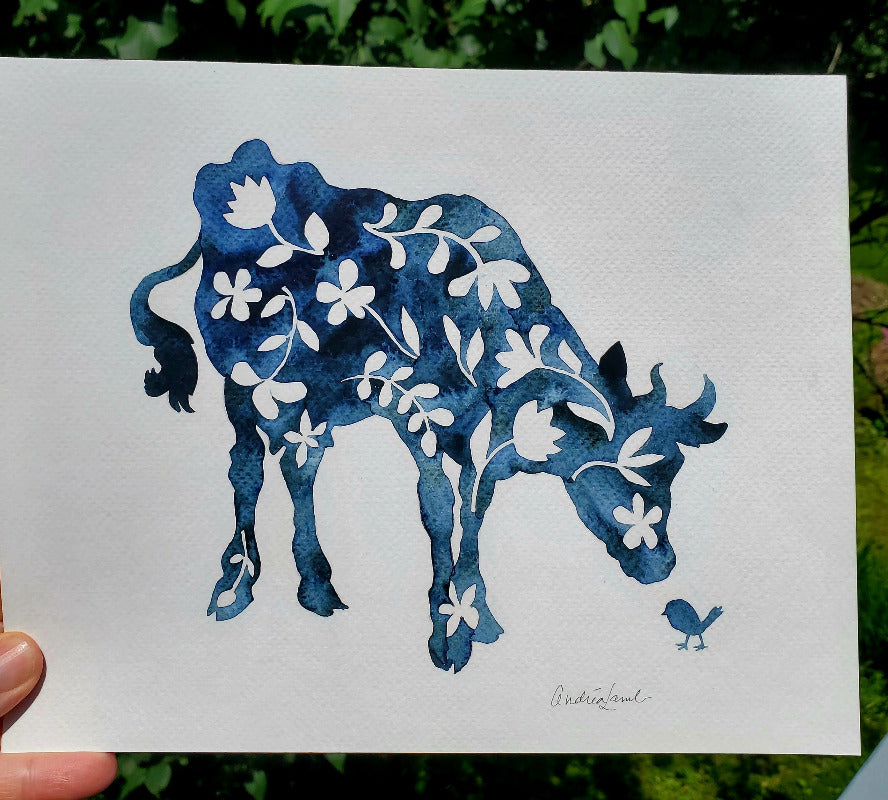 Blue cpw silhouette with floral patterns on a white card held against a green outdoor background.