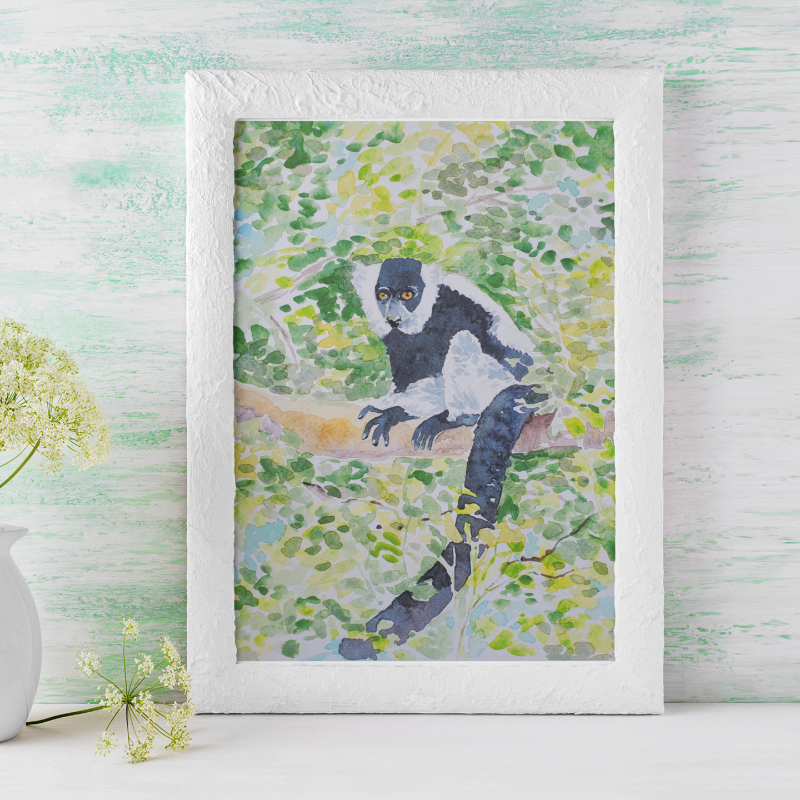 Framed artwork of a lemur on a white surface with a vase of flowers.
