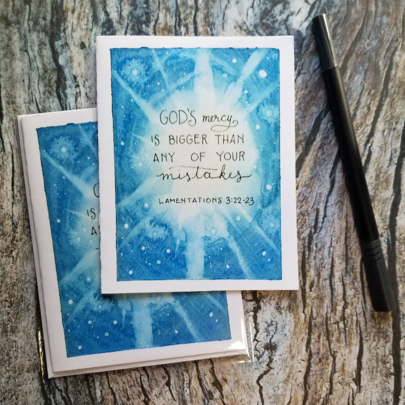 Blue watercolor card with text on a wooden surface
