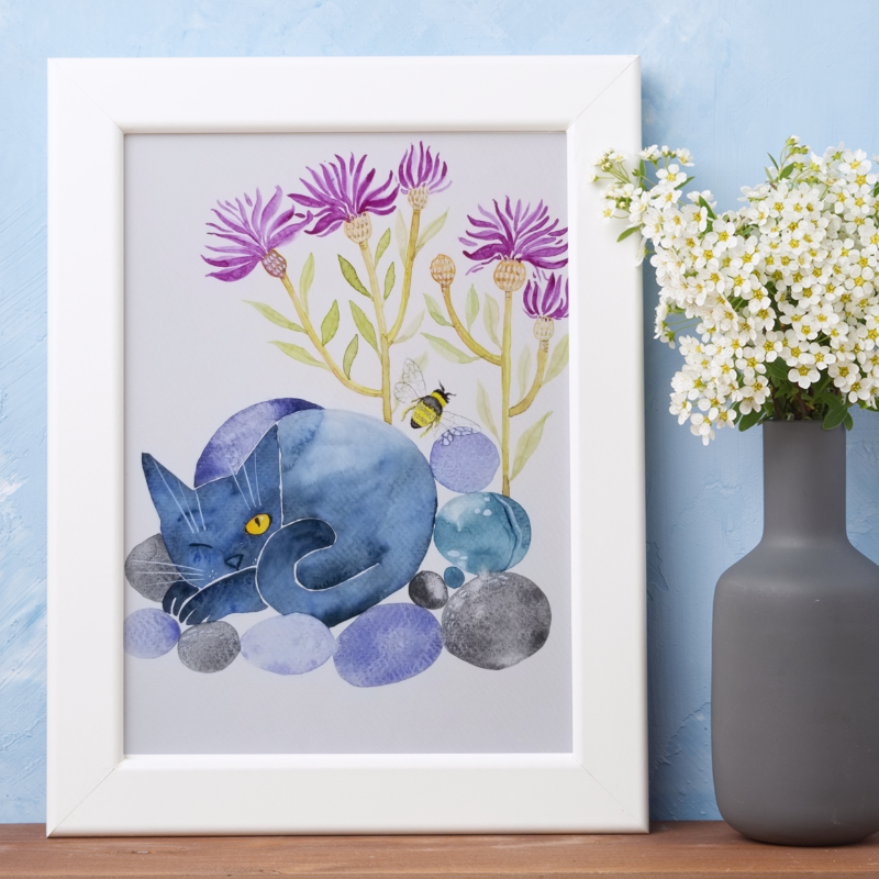 Framed artwork of a blue creature with purple flowers on a blue wall with a vase of white flowers.