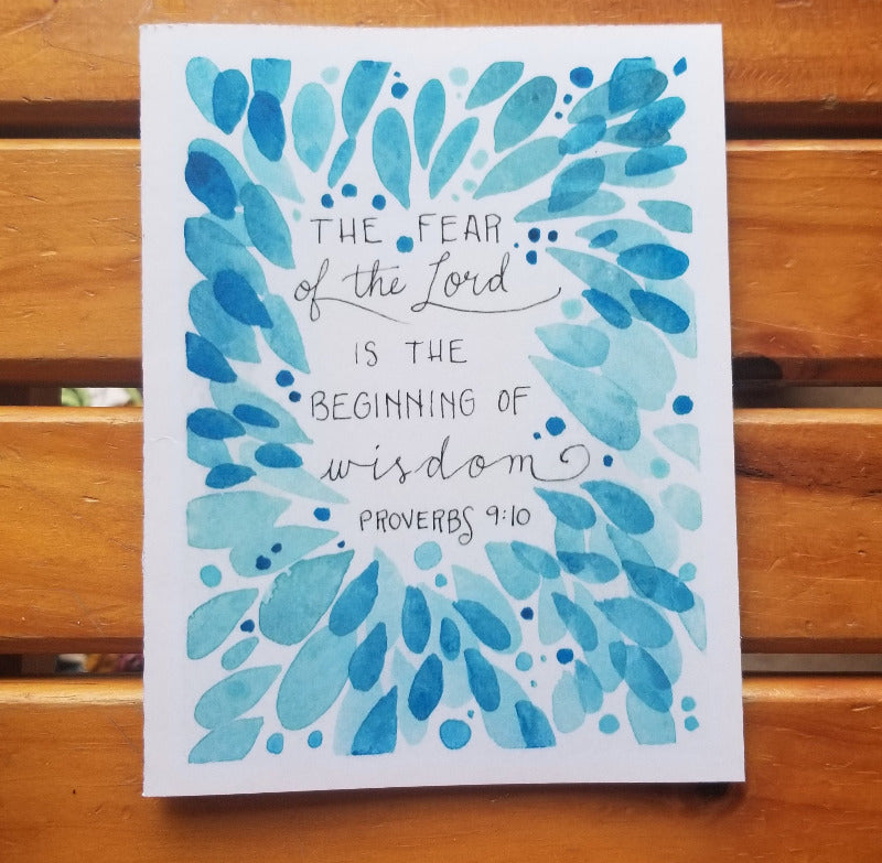 Card with blue leaf design and Proverbs 9:10 text on a wooden surface