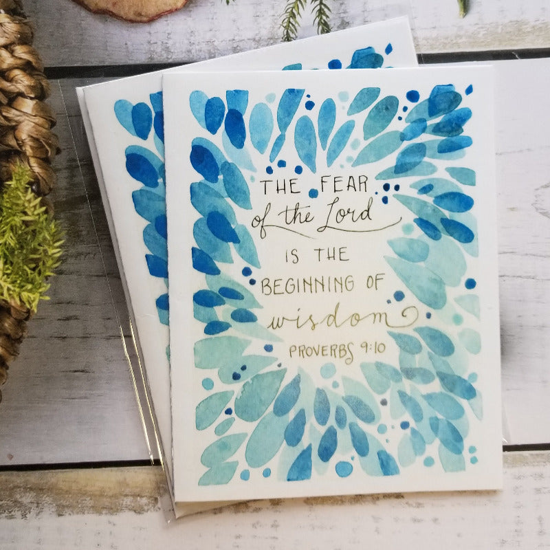 Card with blue floral design and text on a wooden surface with decorative elements.