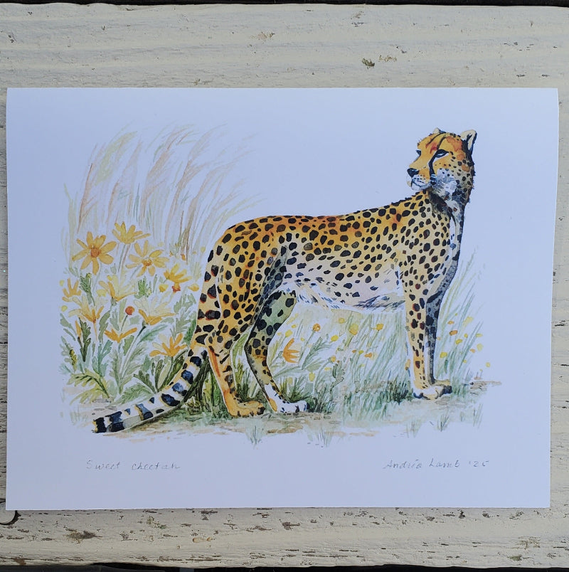A fine art card depicting a painted cheetah standing in grass with yellow flowers, mounted on a distressed white wooden surface.